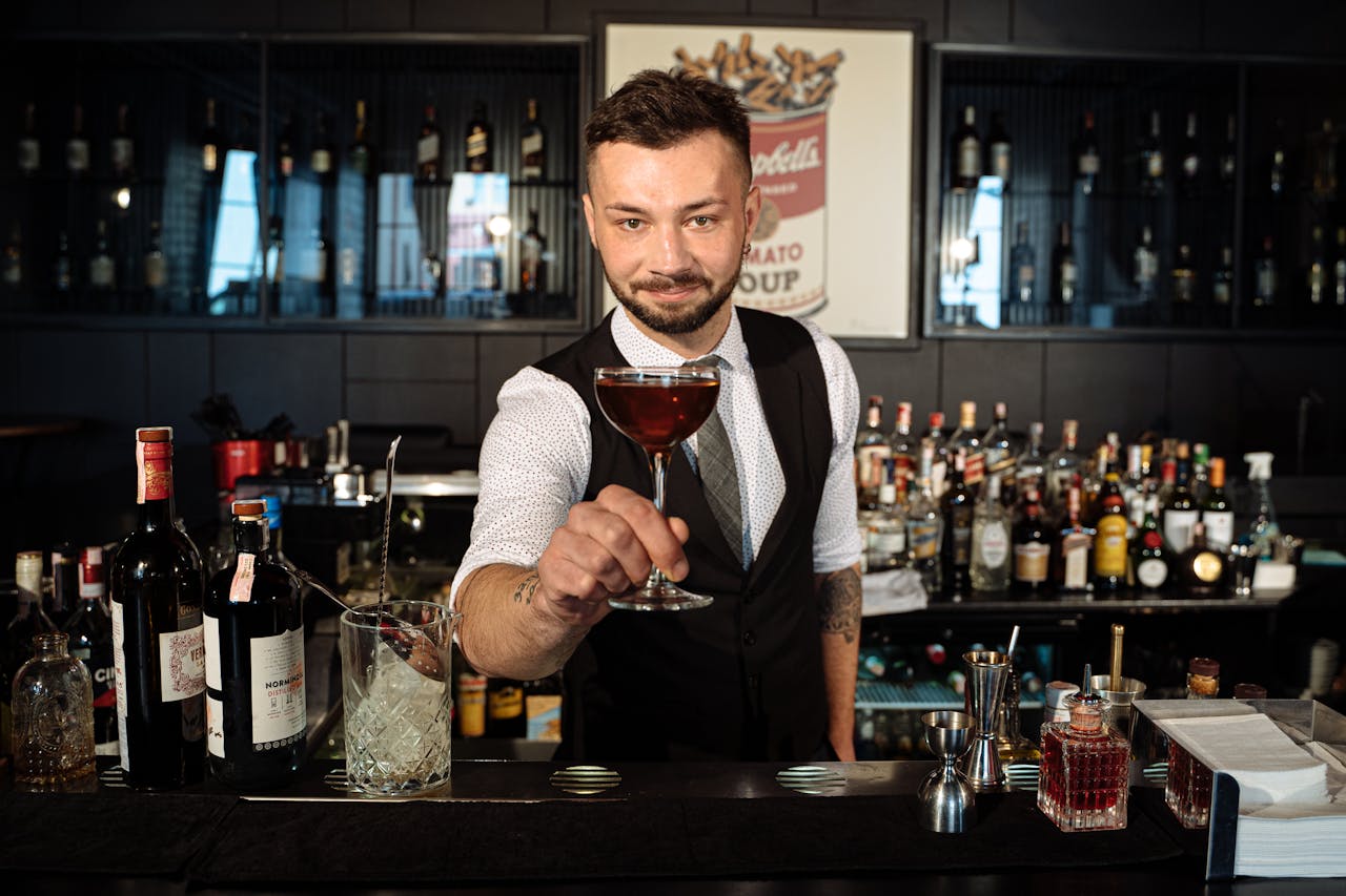 our-experience Bartender offers a crafted cocktail in a stylish bar, showcasing skills and inviting atmosphere.