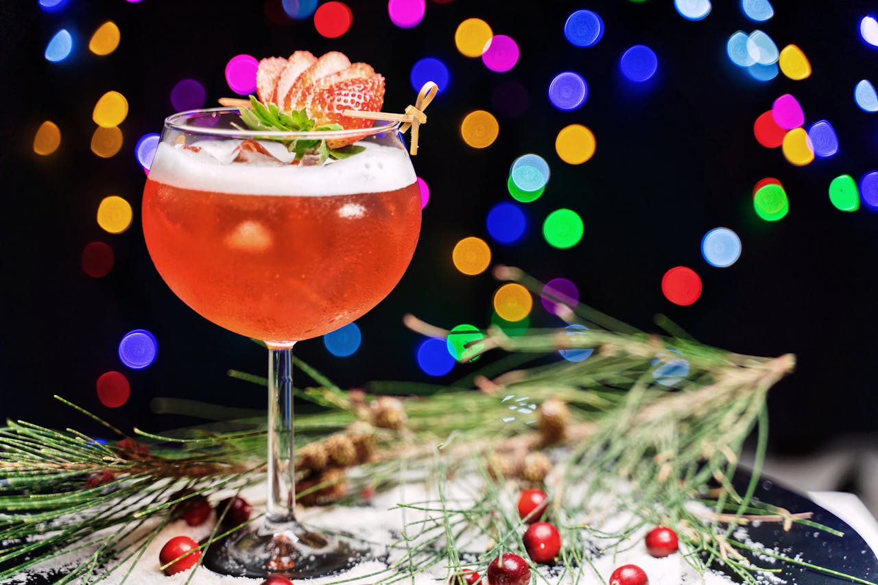 ours-journey A vibrant strawberry cocktail garnished with strawberries and festive decor, against colorful bokeh lights.